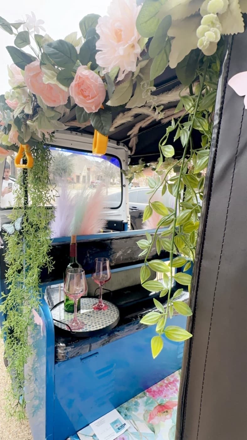 Inside the wedding entrance rickshaw, florals and hanging greenery over the bench seat