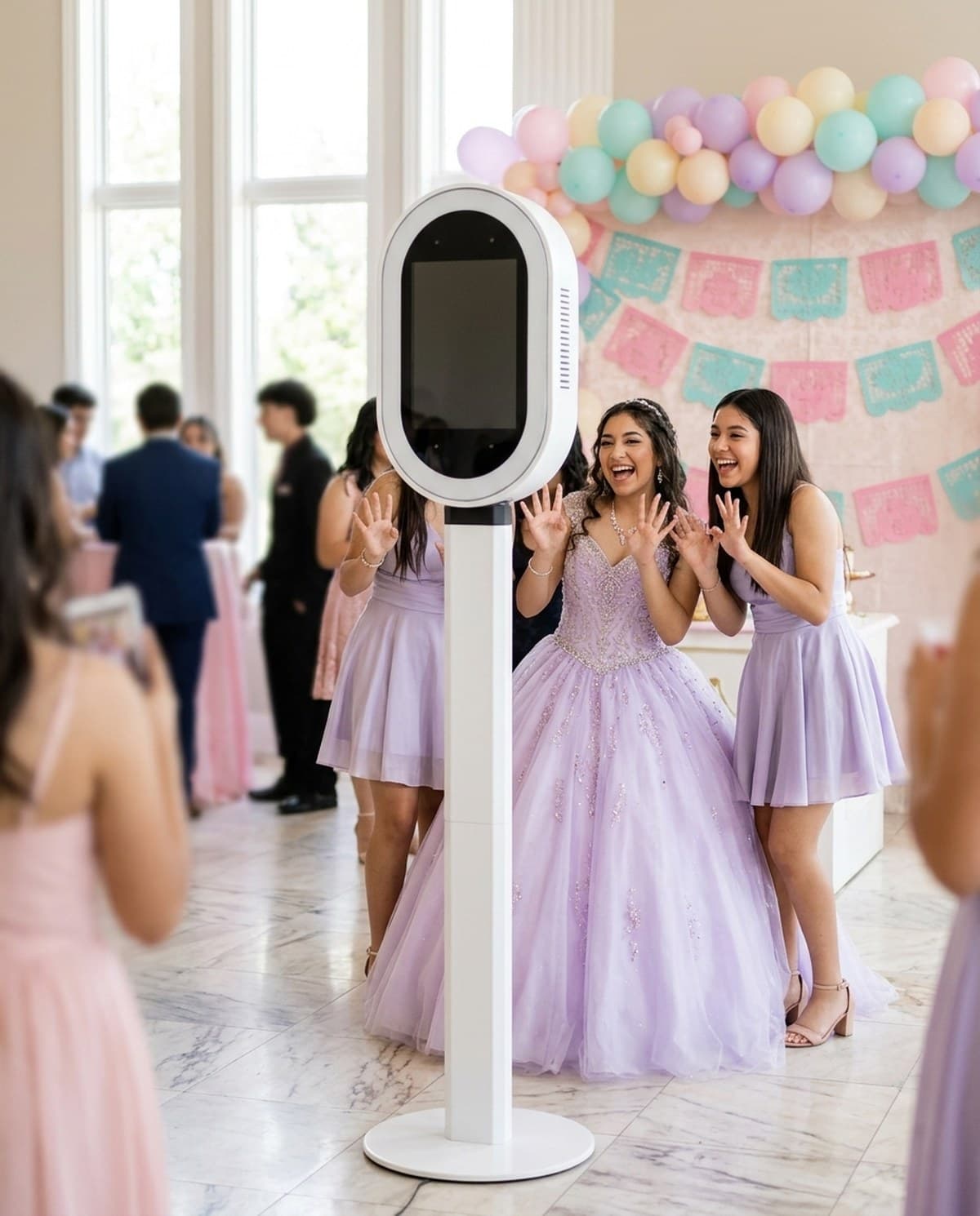 A quinceanera and two friends laughing at the photo booth in a bright event hall.