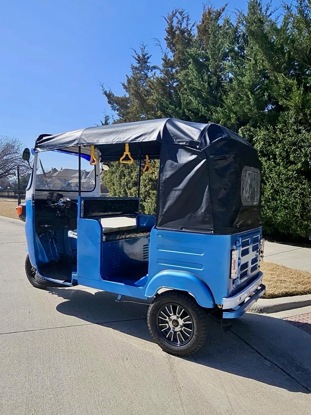 The 2024 blue and white Euro Captain electric tuktuk photographed from the side with the canopy up