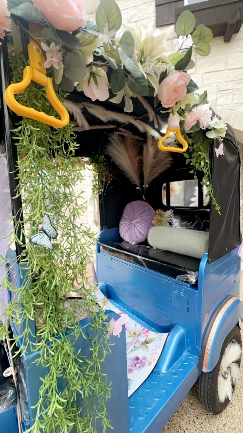 The electric rickshaw with its canopy open and florals over the bench seat, set up and waiting before guests arrive
