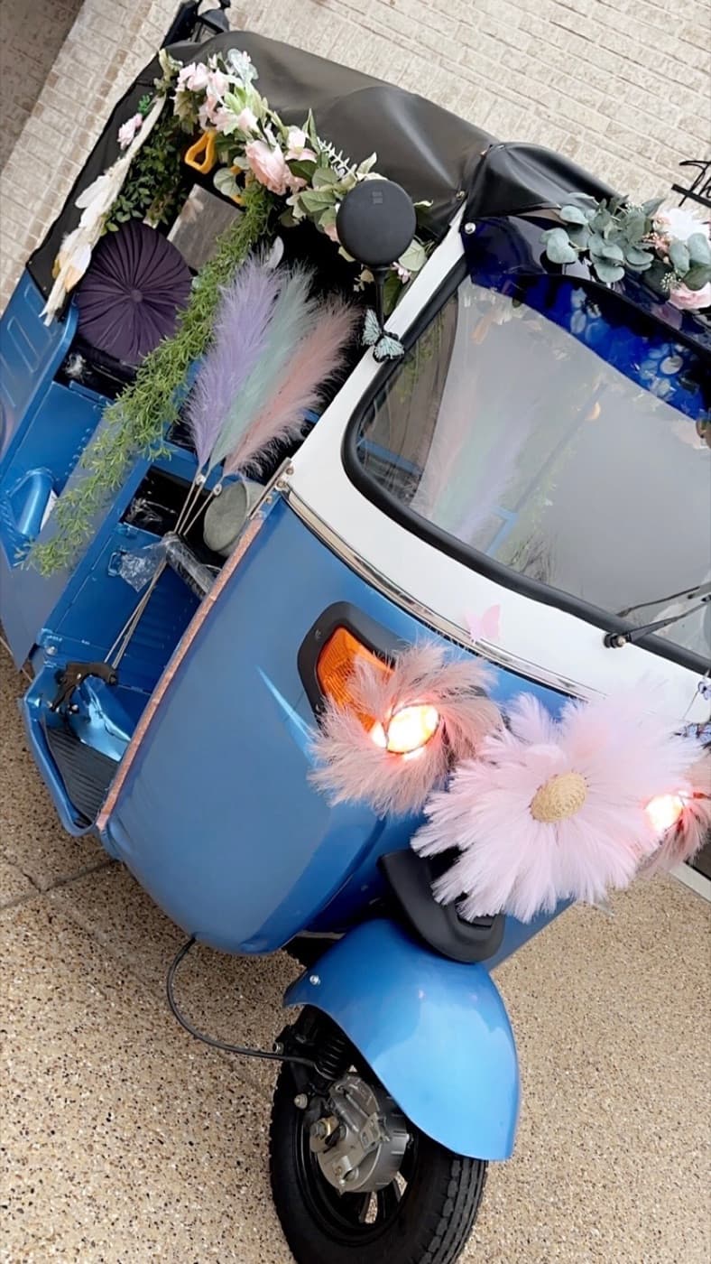 Electric rickshaw dressed in florals and lit up at night for a wedding grand entrance in Dallas-Fort Worth