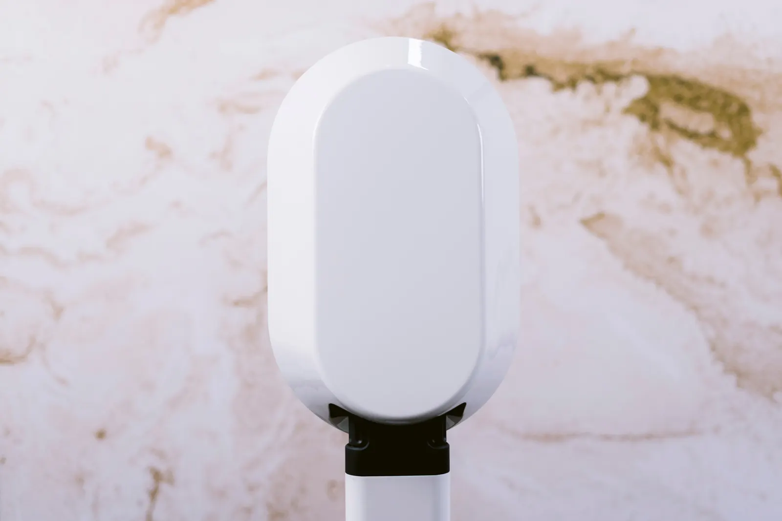 A white oval photo booth head on a slim stand in front of a warm marble-patterned backdrop.